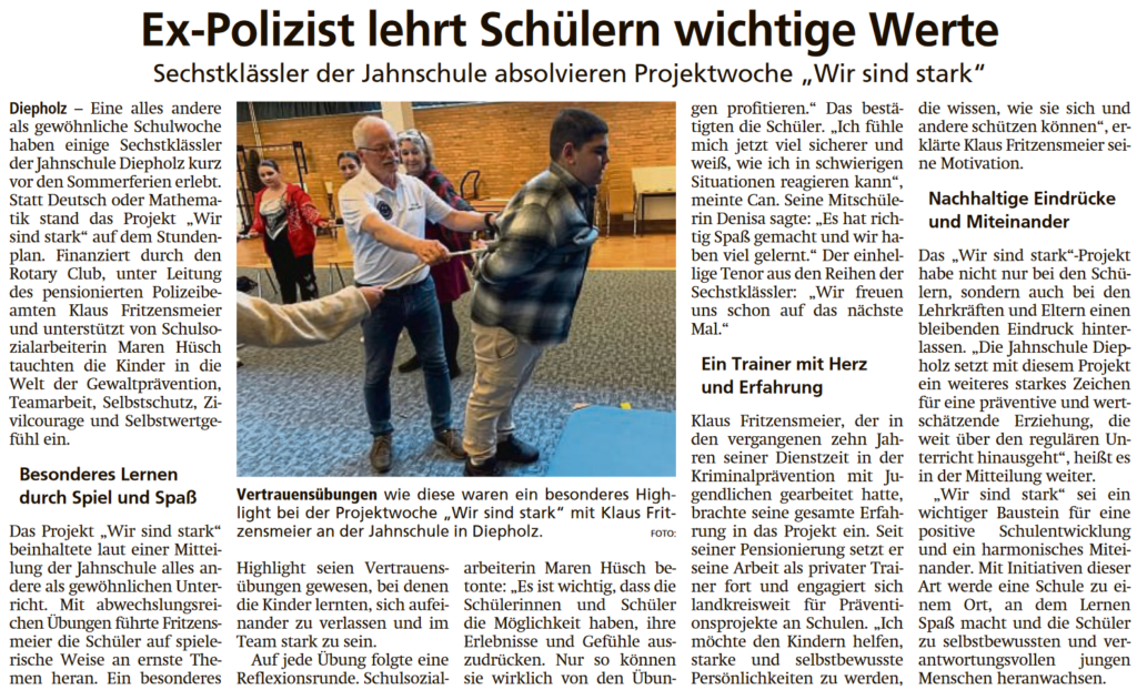 Das Bild zeigt den Zeitungsartikel zum Projekt "Wir sind Stark" an der Jahnschule. In der Mitte des Artikels ist ein Foto abgebildet. Dieses zeigt den Anleiter, wie er gemeinsam mit den Kindern der Lerngruppe eine Person mit Hilfe eines Seils festhält und am Umfallen hindert.